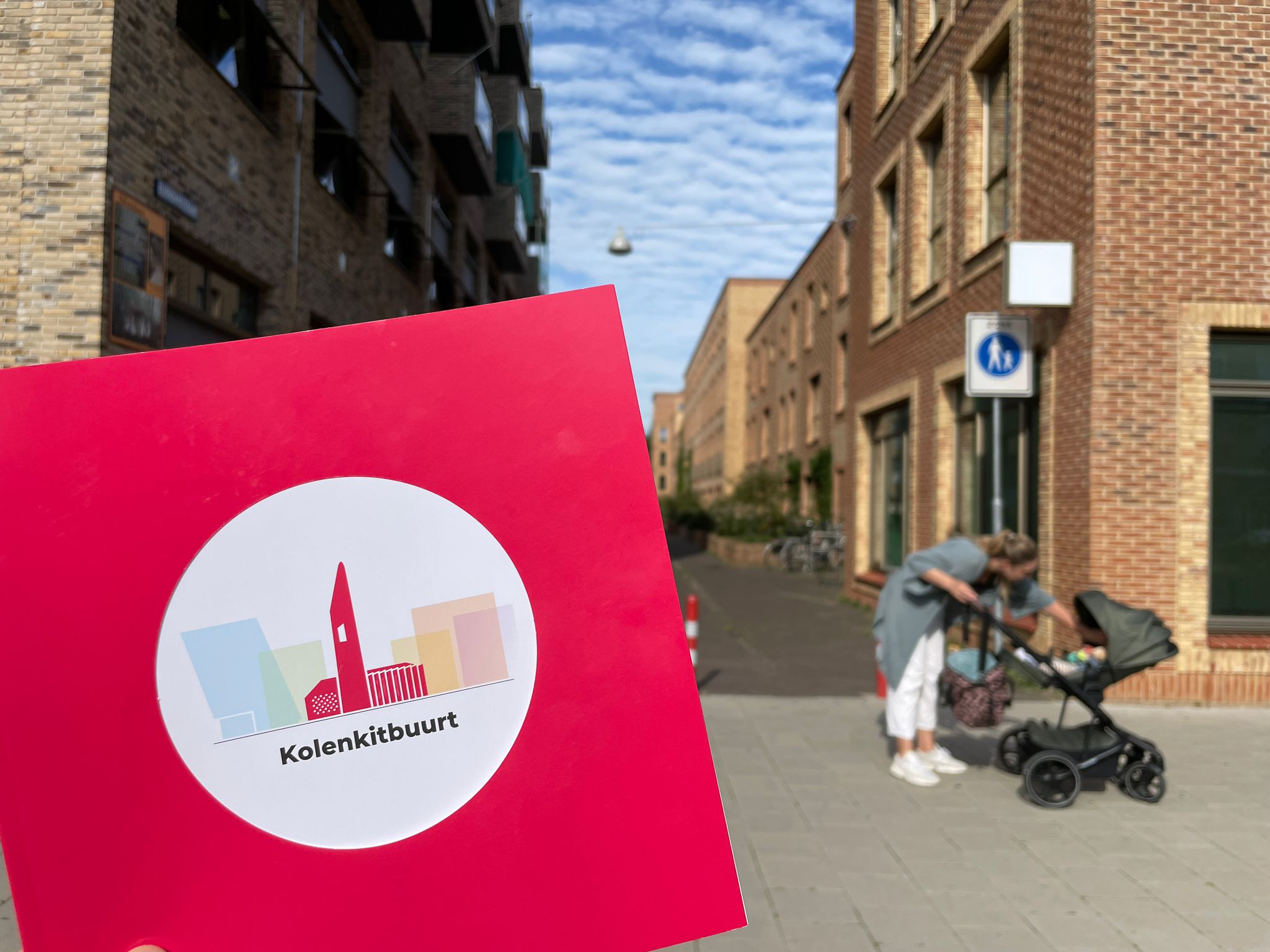 Foto van het boekje over de Kolekitbuurt met op de achtergrond een straat uit die vernieuwde buurt.